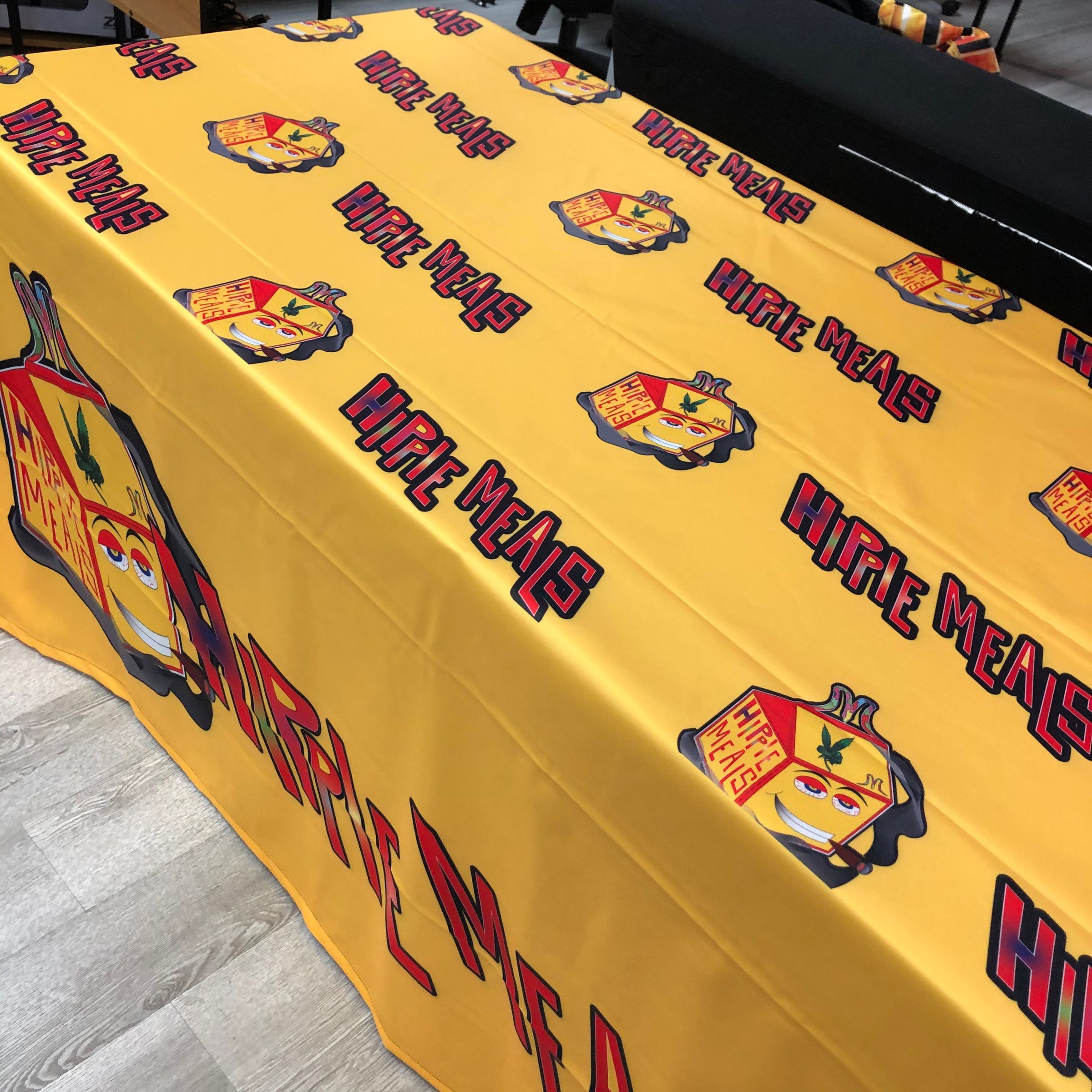 Yellow 6ft fitted table throw with repeating Hippie Meals logo pattern