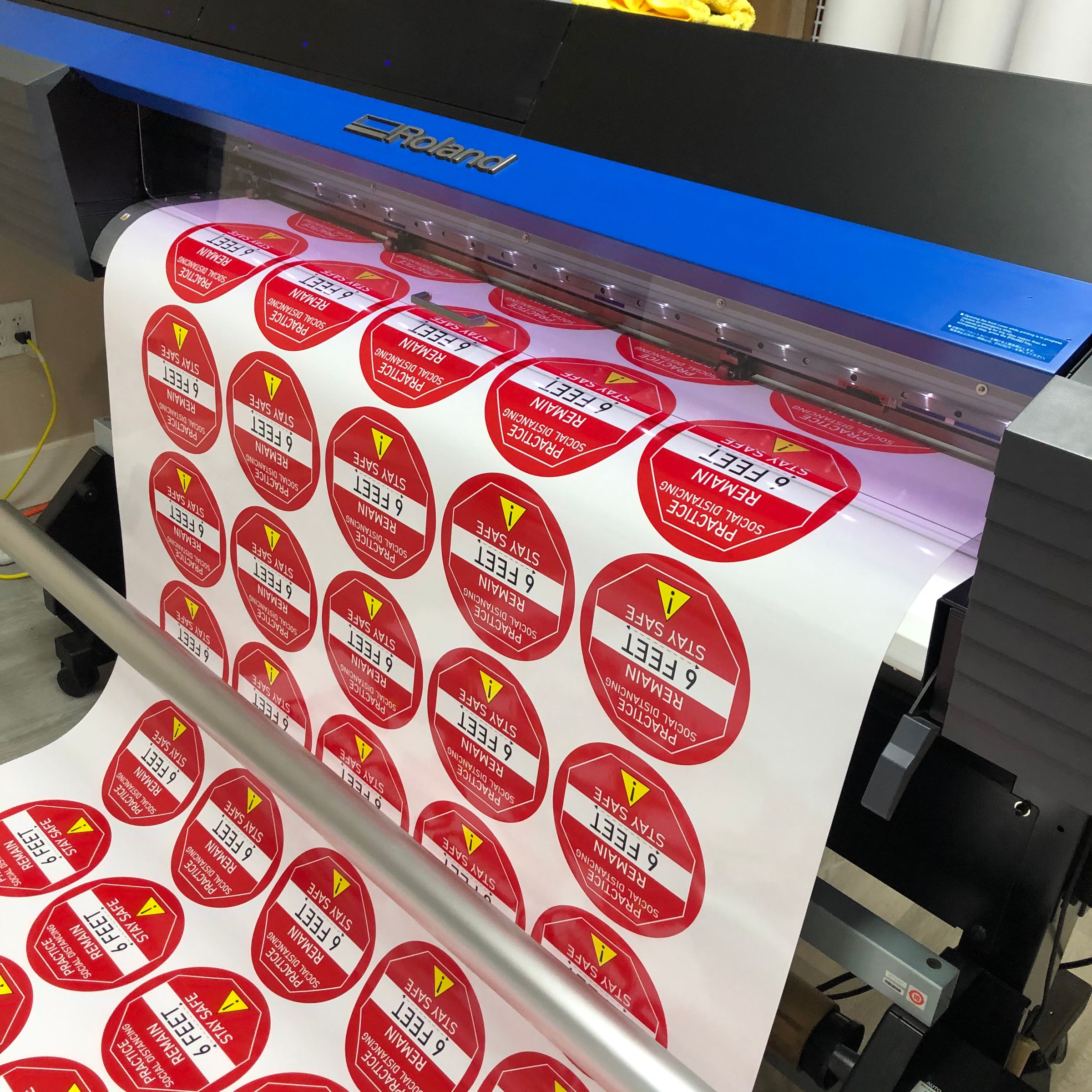 Roland large format printer running round red sticker labels