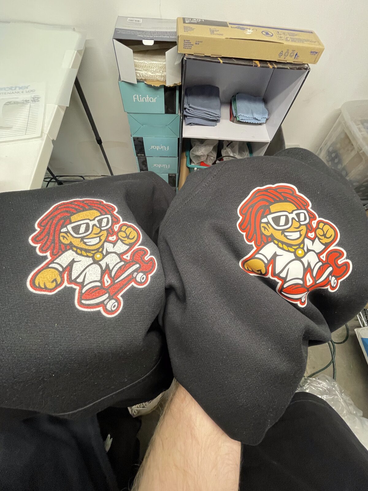 DTG printed cartoon character logo on the sleeves of two black hoodies