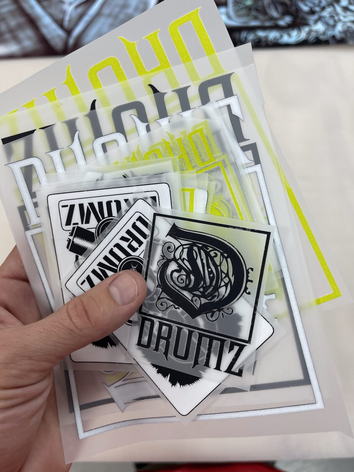 A hand holding several printed DTF transfer sheets before they are pressed onto garments