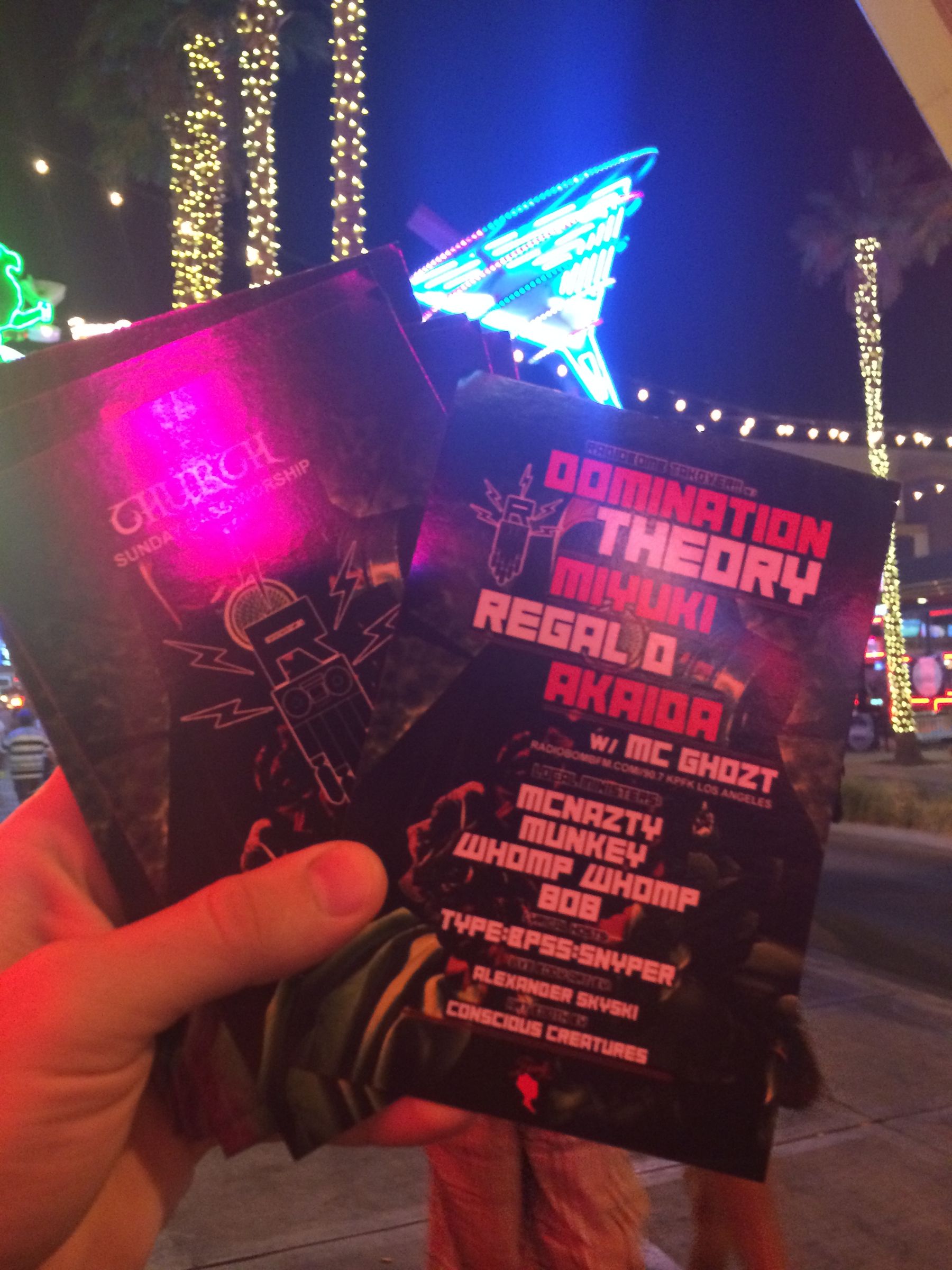 Hand holding a stack of printed club event flyers at night